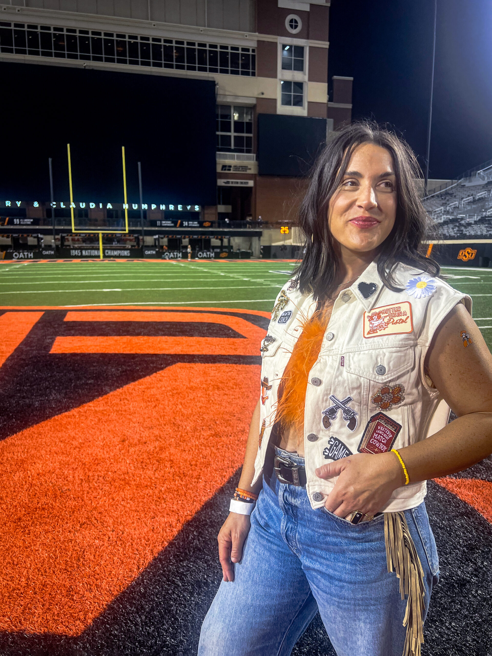 Macca Edwards wearing a custom white denim game-day vest at an Oklahoma State football field